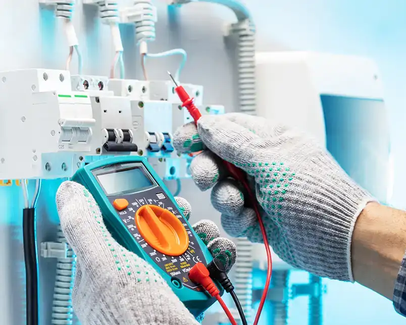 JSE Service and Electric LLC technician using a digital multimeter to test circuit breakers at an electrical panel in Columbia, IL