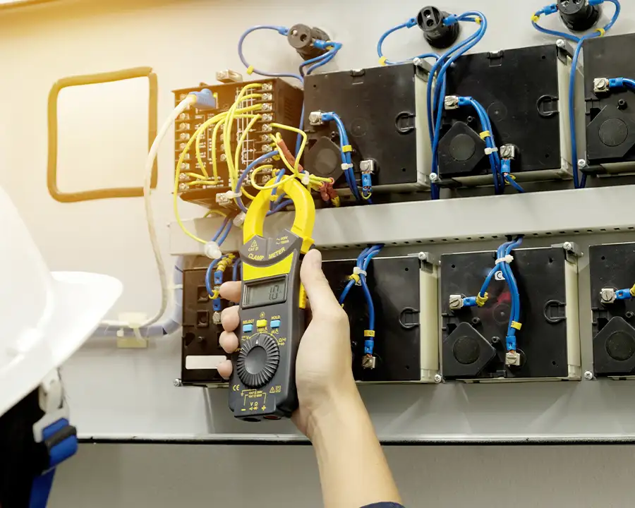 Electrician using a clamp meter to test an industrial electrical control panel — JSE Service and Electric LLC commercial electrical services in O'Fallon, IL and St. Louis, MO