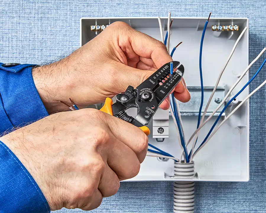 Electrician using wire strippers to prepare wiring inside a junction box — JSE Service and Electric LLC professional wiring services in O'Fallon, IL and St. Louis, MO