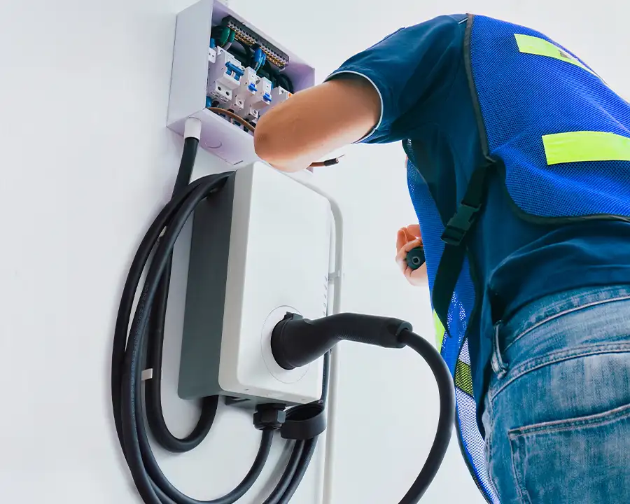 Electrician in safety vest wiring the electrical sub-panel connections for a wall-mounted home EV charger — JSE Service and Electric LLC, O'Fallon, IL and St. Louis, MO