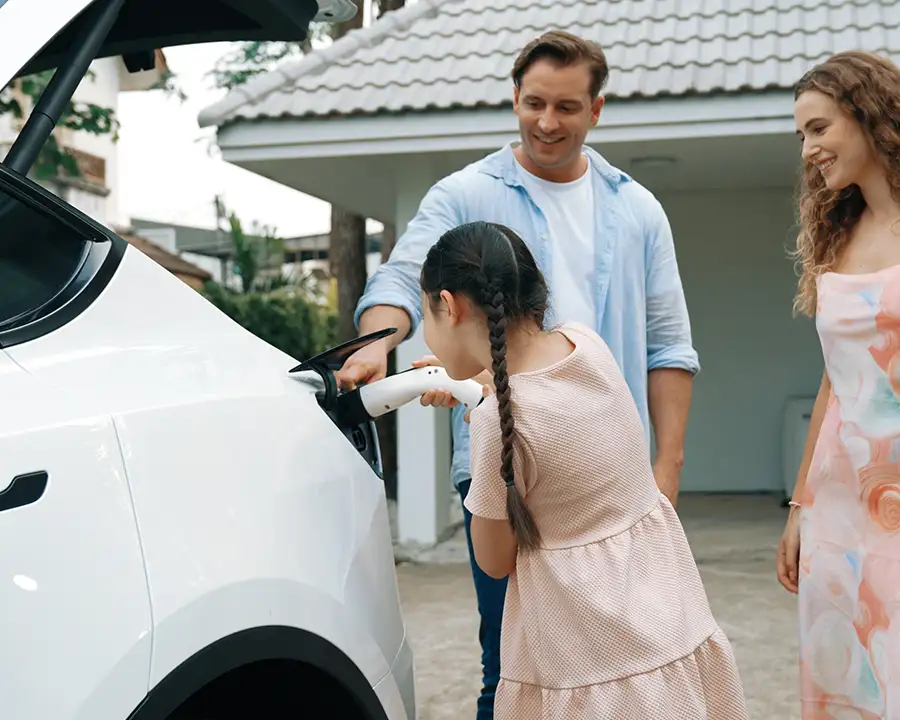 Happy family plugging in their electric vehicle at home using a charger installed by JSE Service and Electric LLC — serving O'Fallon, IL and St. Louis, MO