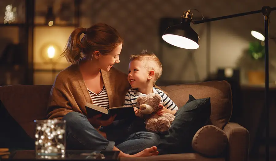 Mother and young child reading together on a couch under warm lamp light at home — JSE Service and Electric LLC reliable interior home lighting services in O'Fallon, IL and St. Louis, MO