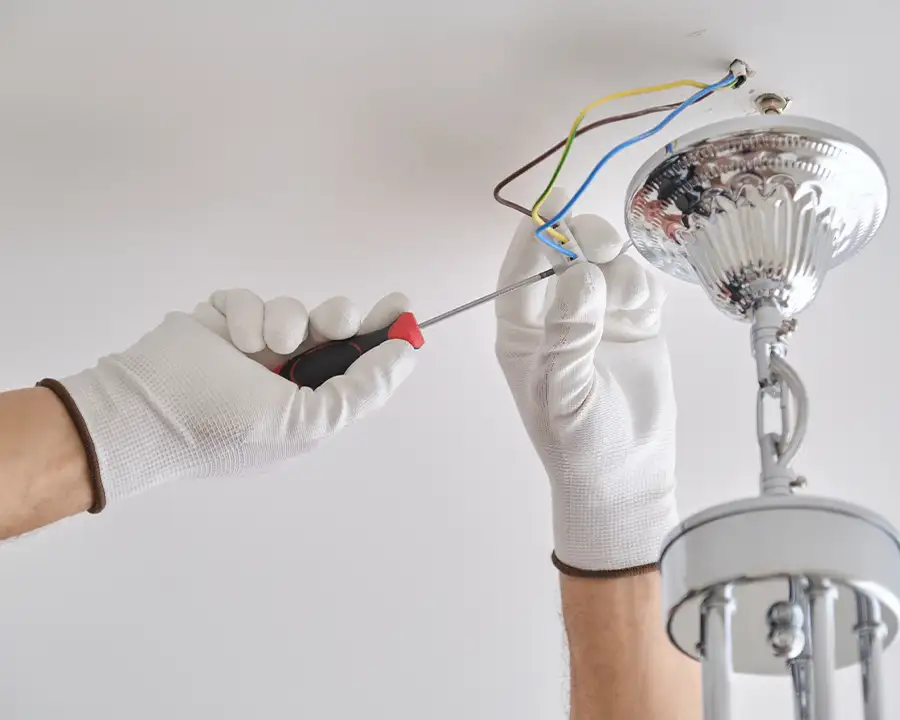 Gloved electrician wiring a ceiling light fixture using a screwdriver — JSE Service and Electric LLC light fixture installation in O'Fallon, IL and St. Louis, MO