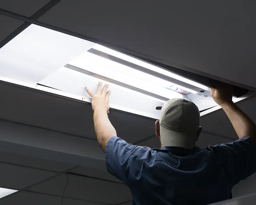 JSE Service and Electric LLC technician installing a recessed fluorescent ceiling light fixture in a commercial building serving O'Fallon, IL and St. Louis, MO.