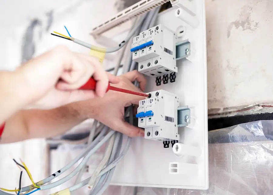 JSE Service and Electric LLC electrician tightening breaker connections with both hands during a panel wiring installation at a Ballwin, MO property